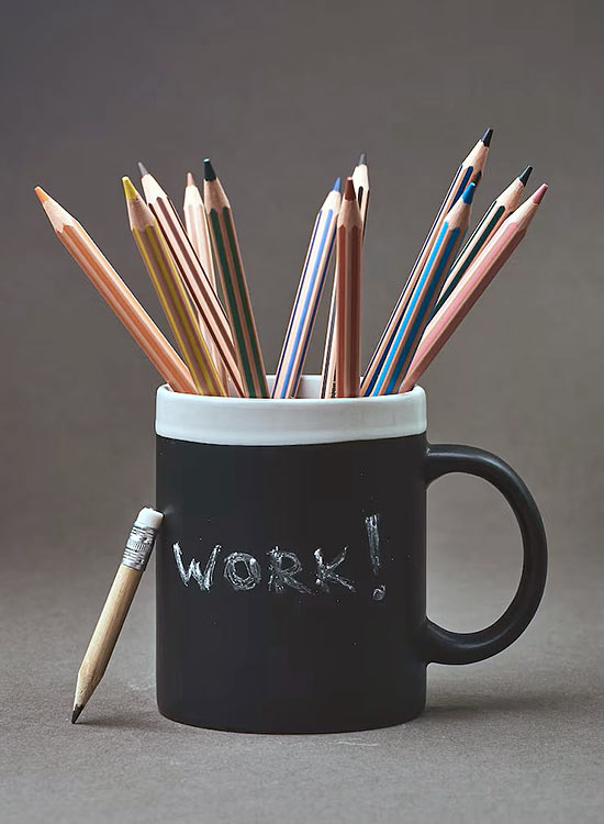 A black cup filled with pencils, featuring a handwritten WORK! message, symbolizing creativity and productivity.