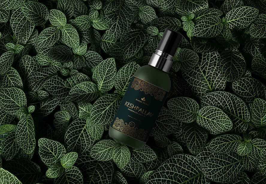 Avimee Herbal Keshpallav Hair Oil Bottle – A natural-themed product presentation featuring the bottle placed on fresh plant foliage.