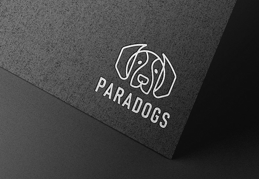 Paradogs Embossed Logo – Elegant silver logo imprinted on dark textured paper, emphasizing sophistication and high-end branding.
